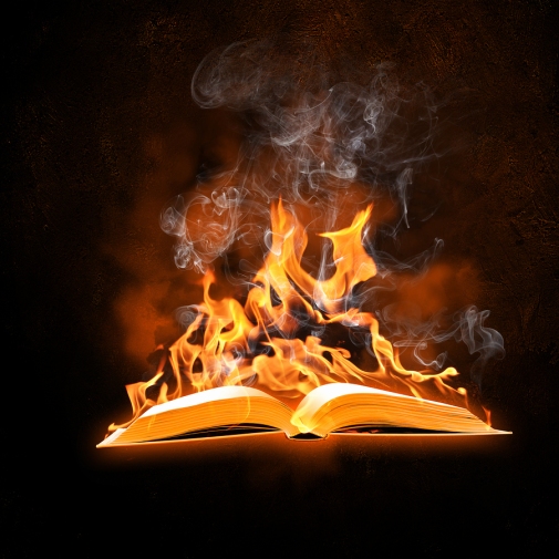 Image of opened burning book against black background